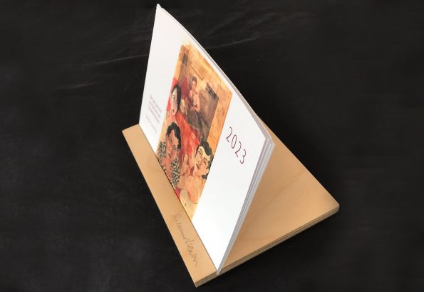 Coronik-Kalender 2023 als Tischvariante mit 13 Bildern von figürlichen Illustrationen auf ganzer Zeitungsseite, die nach Verwendung als Postkarten ausgeschnitten werden können.